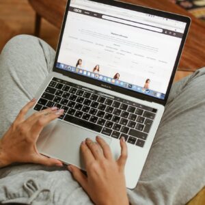 Person browsing an online shopping website on a laptop while relaxing indoors.